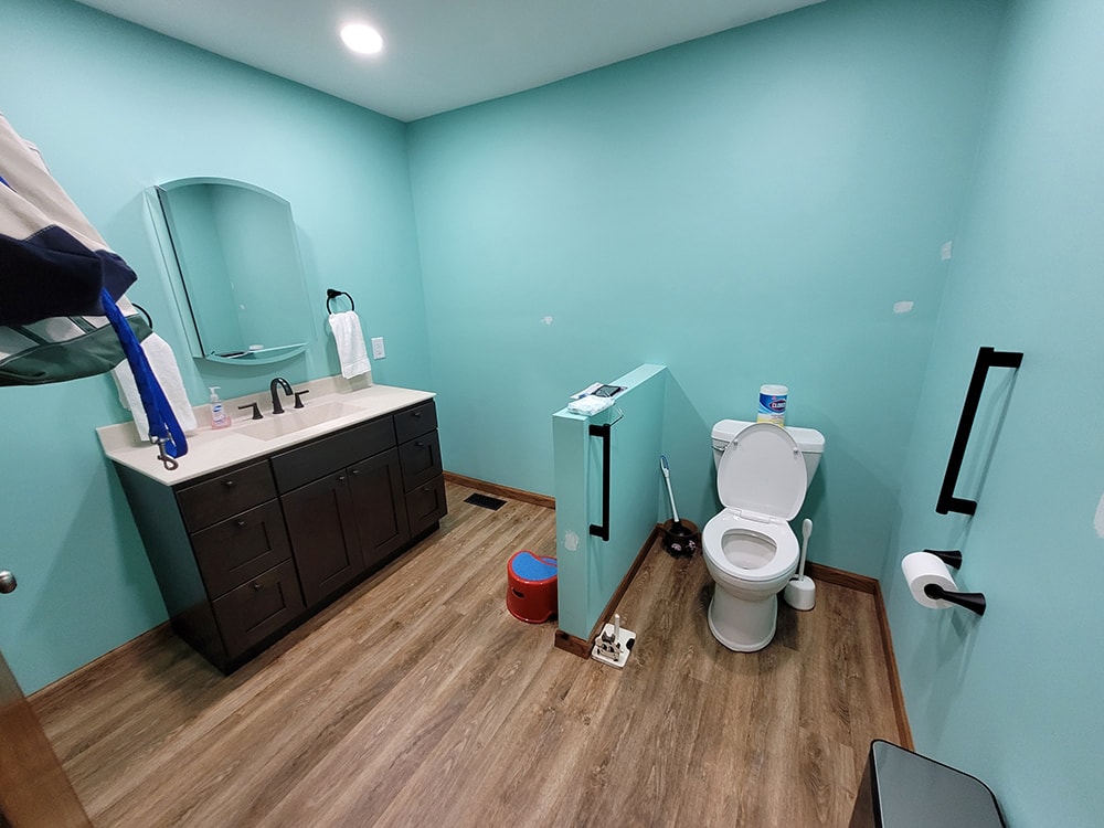 Siding, bathroom, garage & 1/2 bath — after: completed 1/2 bath with turquoise walls, dark vanity, and wood-look flooring — Attica, Ohio