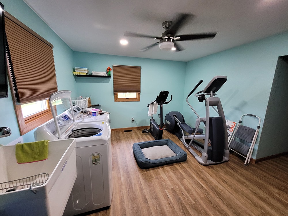 Siding, bathroom, garage & 1/2 bath — after: completed utility and fitness room with turquoise walls, washer/dryer, and exercise equipment — Attica, Ohio