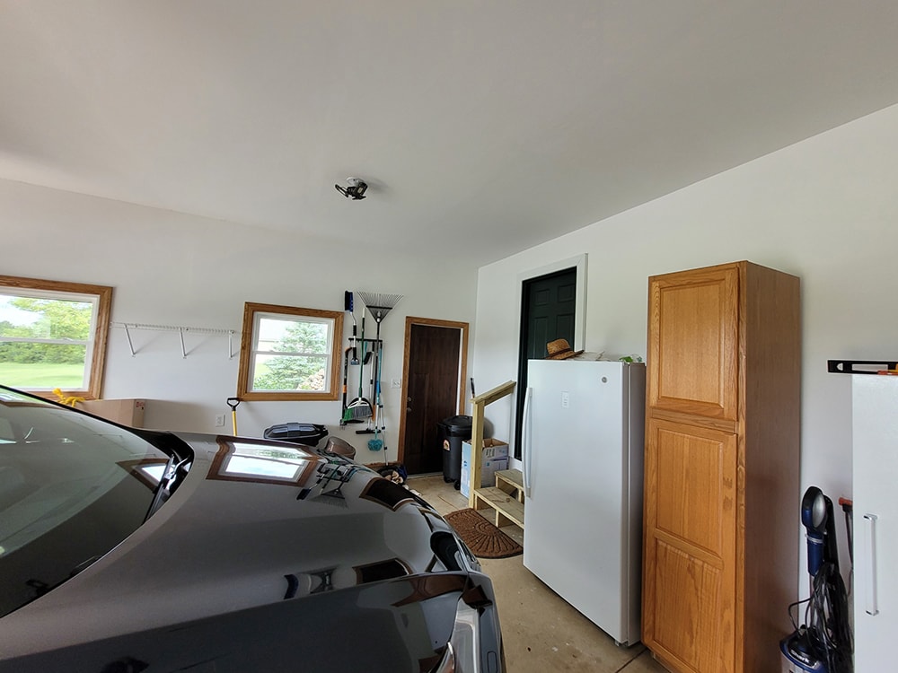 Siding, bathroom, garage & 1/2 bath — after: completed garage interior with drywalled walls and clean finish — Attica, Ohio
