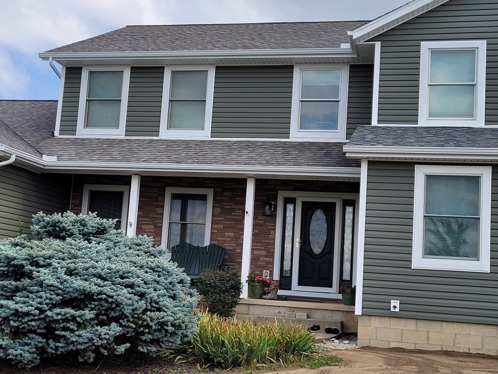 Siding, bathroom, garage & 1/2 bath — after: completed front entry close-up with new gray siding and brick accent — Attica, Ohio