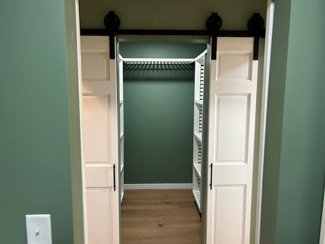 Bathroom/closet addition — after: completed walk-in closet with barn doors, white shelving, and hardwood floor — Findlay, Ohio