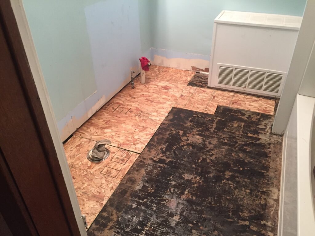 Bathroom remodel Findlay — during: subfloor demo with OSB patches and rotted floor exposed, Findlay, Ohio