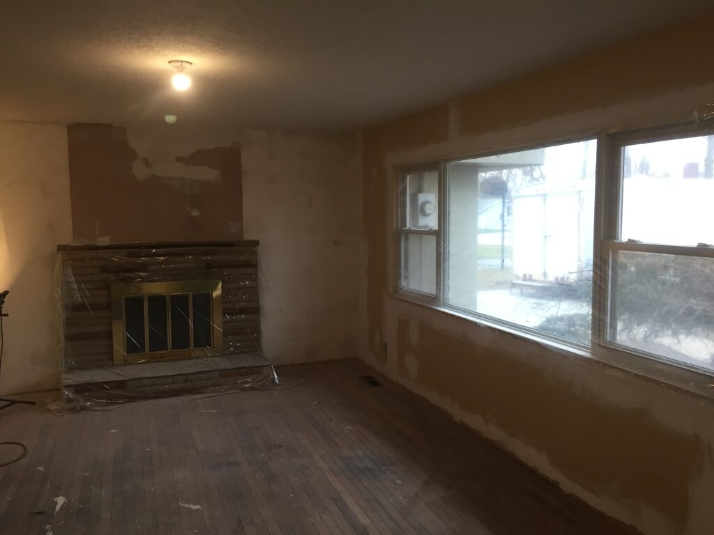 Complete home remodel Findlay — before: living room with fireplace, patched drywall and original hardwood, Findlay, Ohio