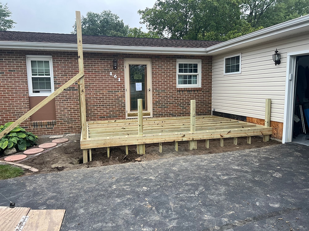 Composite deck with flat roof — during construction: treated lumber framing and posts installed over driveway — Findlay, Ohio