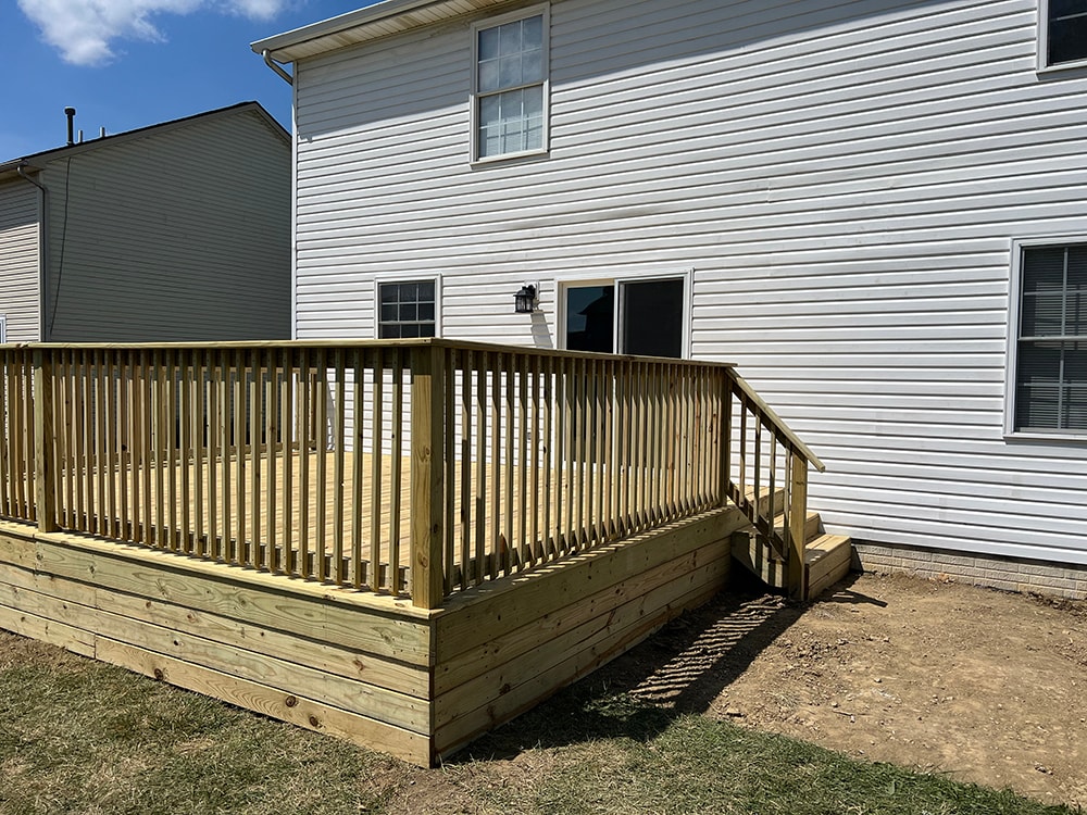 Deck addition — after: close side view of new treated deck with vertical spindle railing and corner stairs, Findlay, Ohio