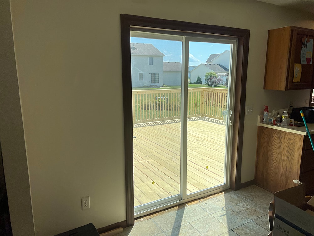 Deck addition — interior after: new sliding glass patio door from inside kitchen looking out to completed treated lumber deck and backyard, Findlay, Ohio