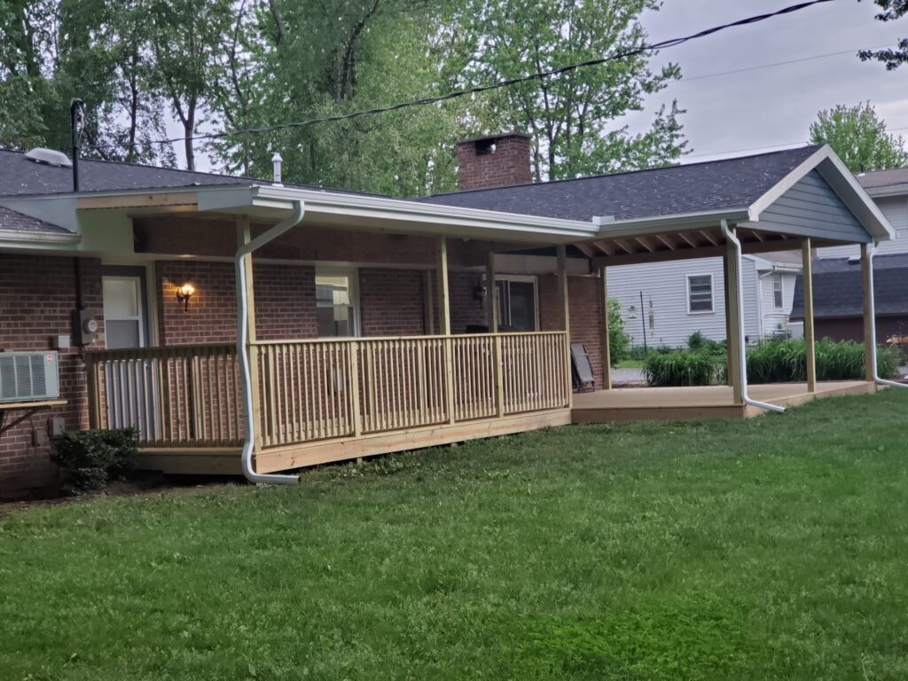 Deck addition Findlay — after: completed covered deck with treated wood railing, white gutters, and screened gable section in overcast light, Findlay, Ohio