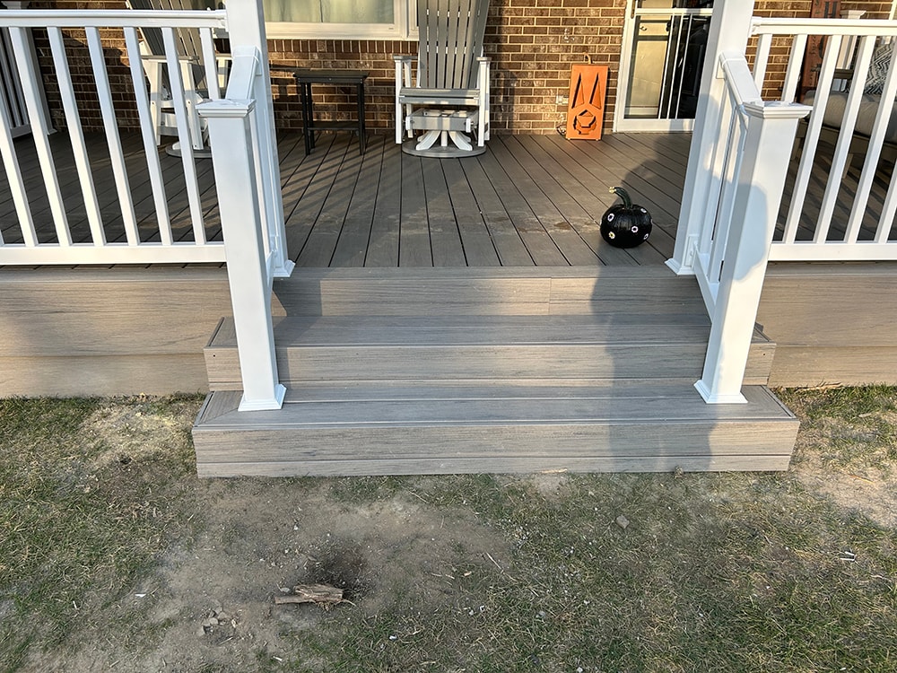 Composite deck with gable roof — after: closeup of gray composite deck steps with white railing posts and Halloween decor — Bluffton, Ohio
