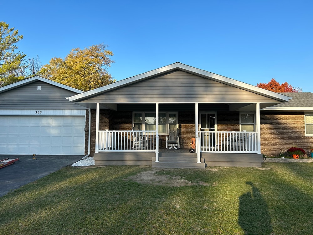 Composite deck with gable roof — after: completed full front view with new gray siding, white railing, and fall foliage — Bluffton, Ohio
