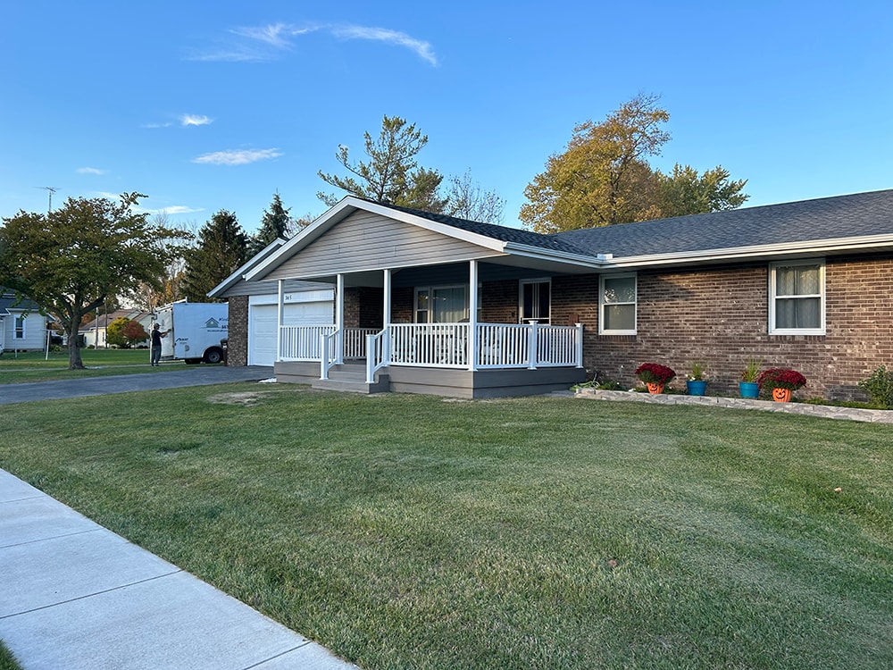 Composite deck with gable roof — after: street view of completed home with new deck, gable roof, and gray siding — Bluffton, Ohio