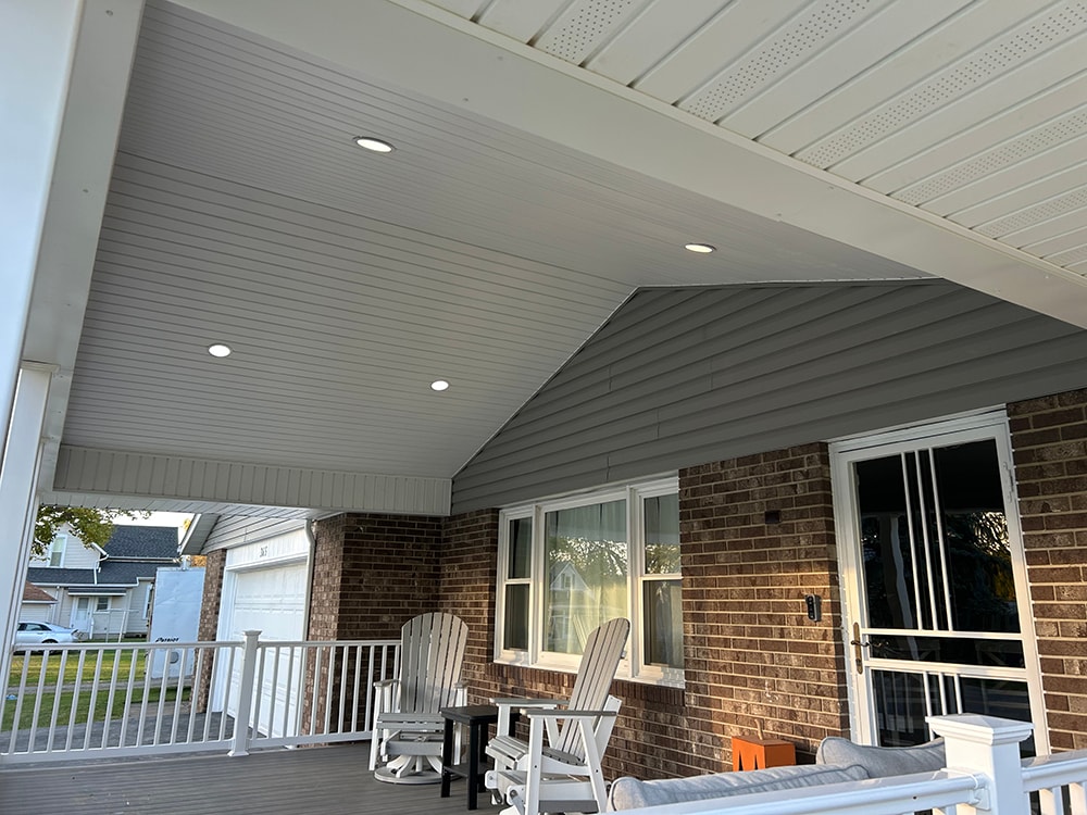 Composite deck with gable roof — after: under-roof view showing beadboard ceiling with recessed lights and Adirondack chairs — Bluffton, Ohio