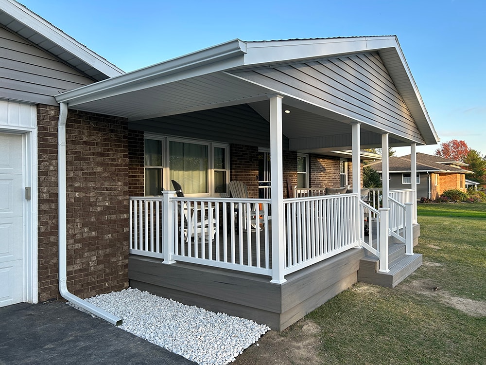 Composite deck with gable roof — after: side angle view of completed deck with white railing, gable roof, and white rock landscaping — Bluffton, Ohio