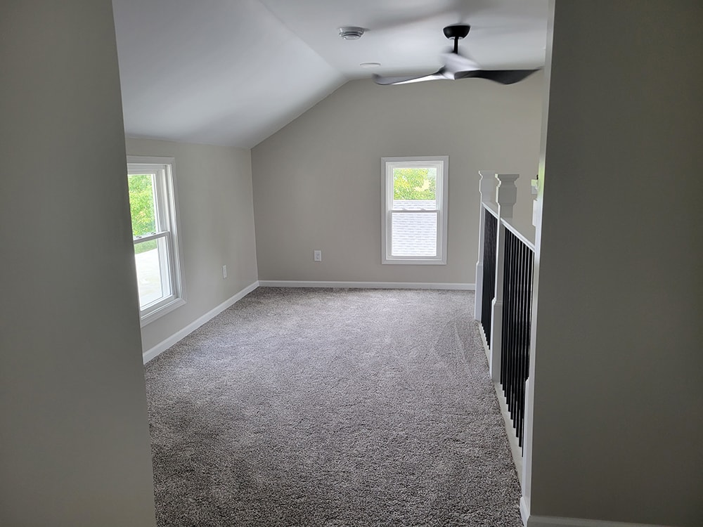 Entire house remodel — after: upstairs loft/bonus room with vaulted ceiling, gray carpet, and ceiling fan — Arlington, Ohio