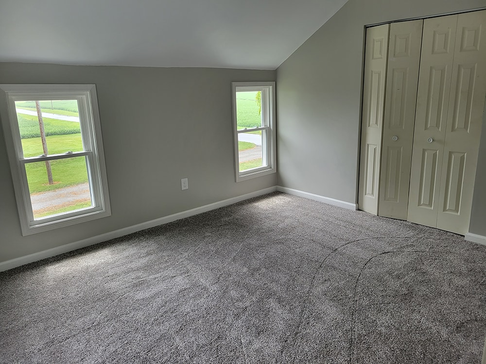 Entire house remodel — after: upstairs bedroom with gray walls, gray carpet, and closet doors — Arlington, Ohio