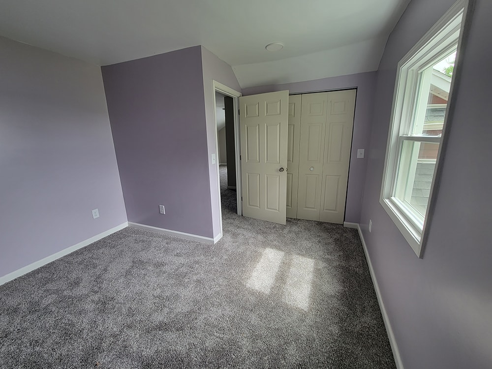 Entire house remodel — after: upstairs bedroom with lavender walls, gray carpet, and closet — Arlington, Ohio