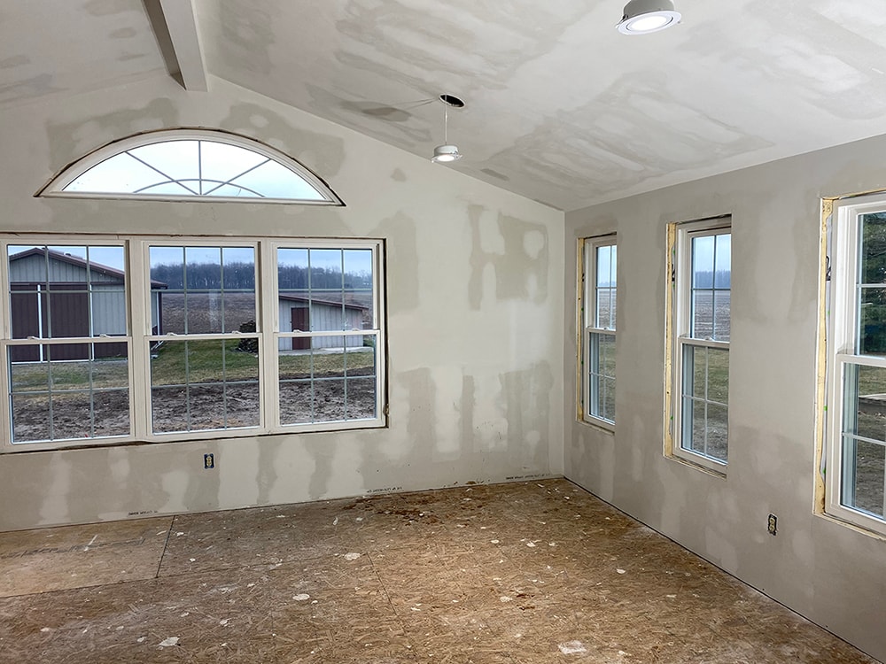 Room addition Fostoria — interior drywall mudded with arched transom window, vaulted ceiling, and large picture window overlooking fields, Fostoria, Ohio