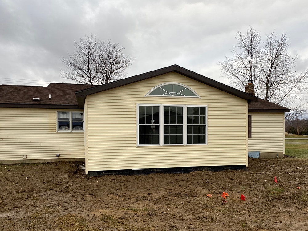 Room addition Fostoria — completed exterior front gable view with arched transom window, picture window, cream siding, and dark brown roof, Fostoria, Ohio