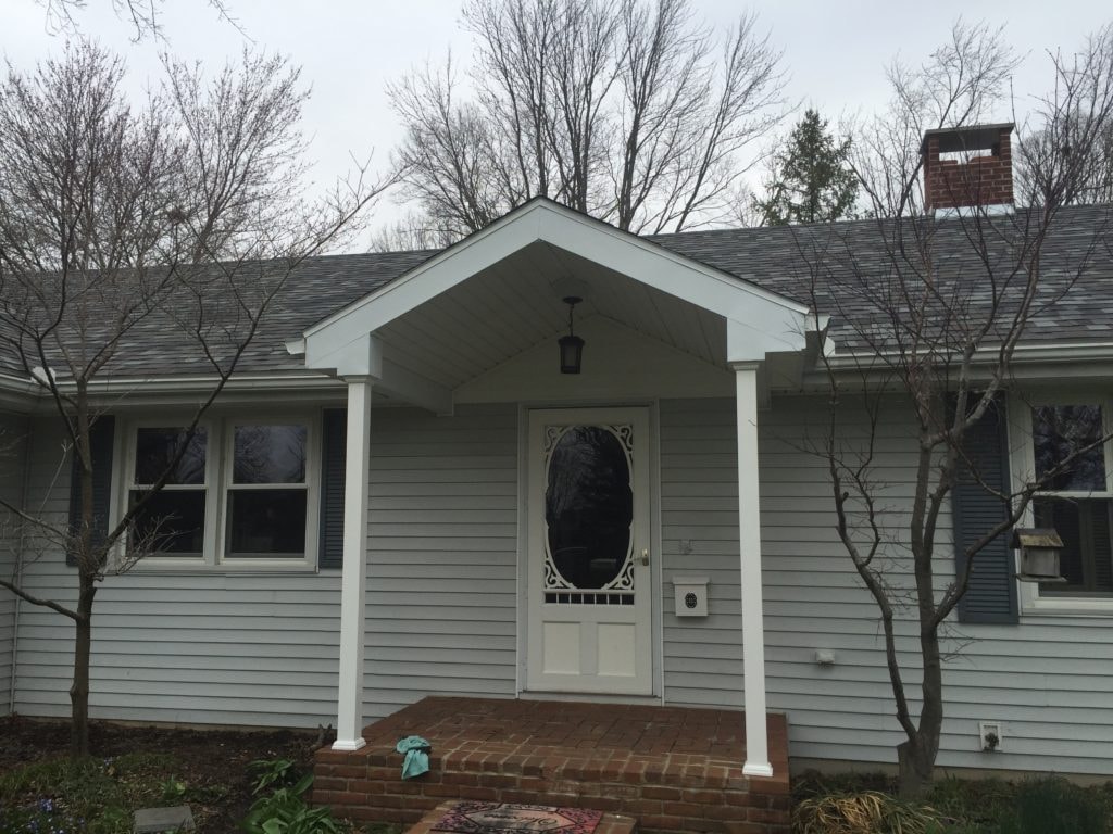 Front porch roof addition Findlay — after: finished gable porch with white columns, pendant light, and brick steps, close-up view, Findlay, Ohio