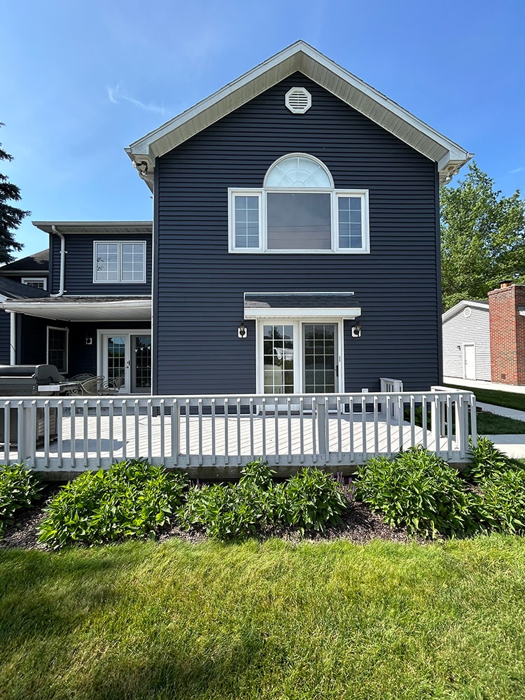 New siding — during: front of home with new dark navy siding nearly complete, trim and window wrapping finished, rural Ohio