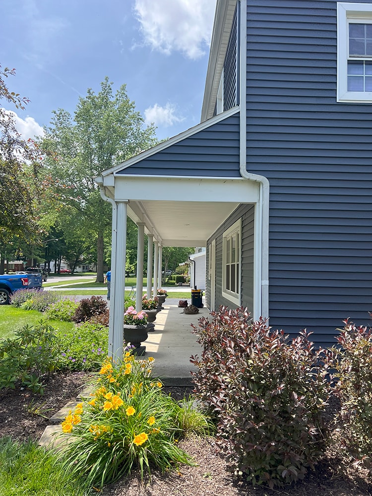 New siding — during: front of home with new dark navy siding partially installed on upper section, rural Ohio