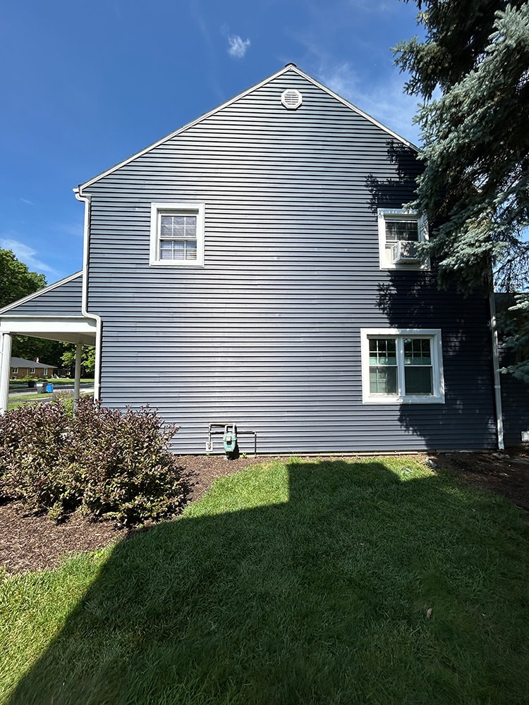New siding — during: rear view with new dark navy siding on addition and original white siding on main home, rural Ohio