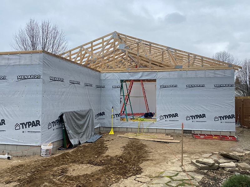 Large home addition — exterior wrapped in Typar house wrap with roof trusses set and ladder staging, Findlay, Ohio