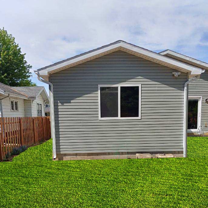 Large home addition — completed exterior side view with gray vinyl siding, new window, and lush green lawn, Findlay, Ohio