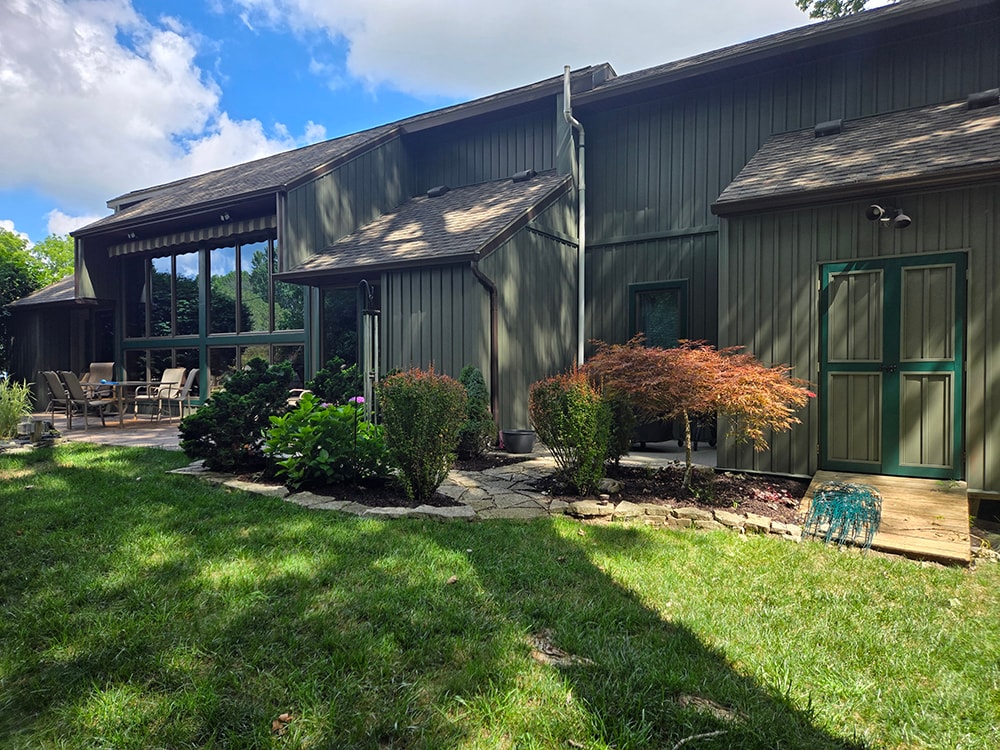 New board and batten siding — before: rear exterior with original dark siding and patio area — Findlay, Ohio