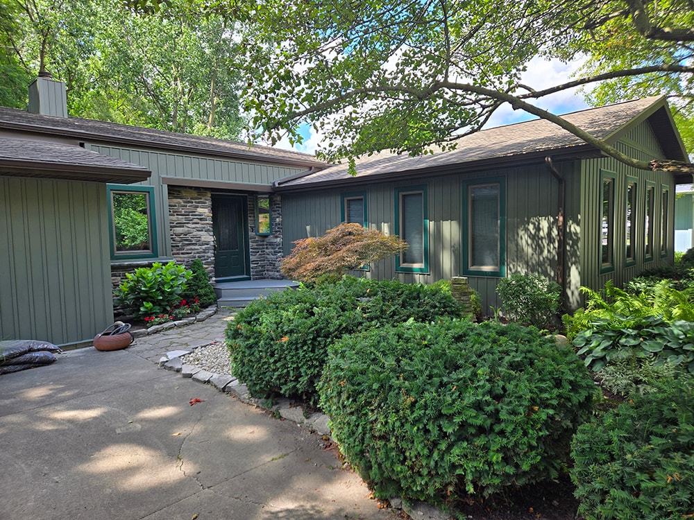 New board and batten siding — after: front entry with new green-gray siding and stone accents — Findlay, Ohio