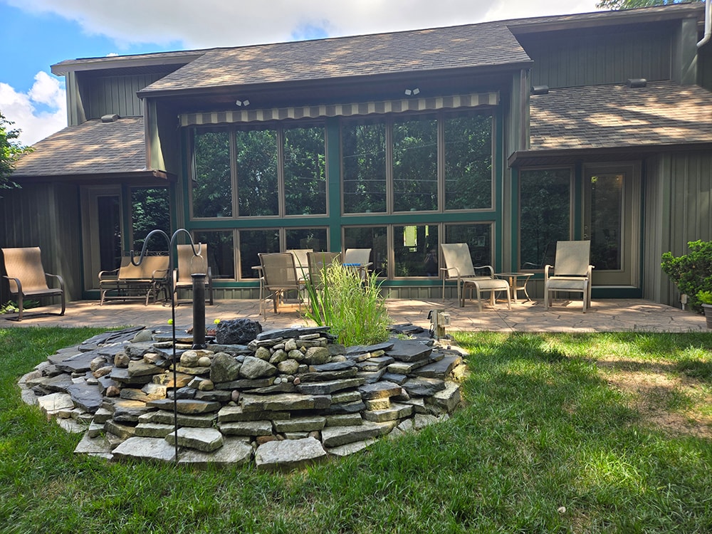 New board and batten siding — before: rear exterior with stone fire pit and patio seating — Findlay, Ohio