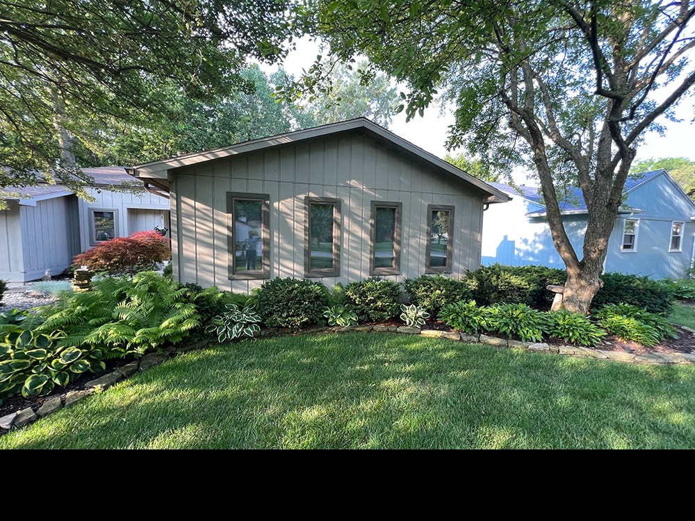 New board and batten siding — after: side wing with new siding and lush landscaping — Findlay, Ohio
