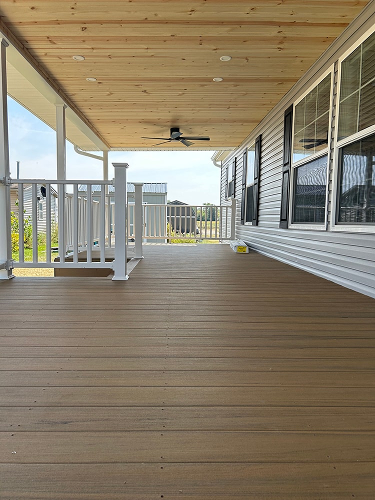 New composite deck with roof — deck surface view along home with cedar ceiling and ceiling fan — Findlay, Ohio