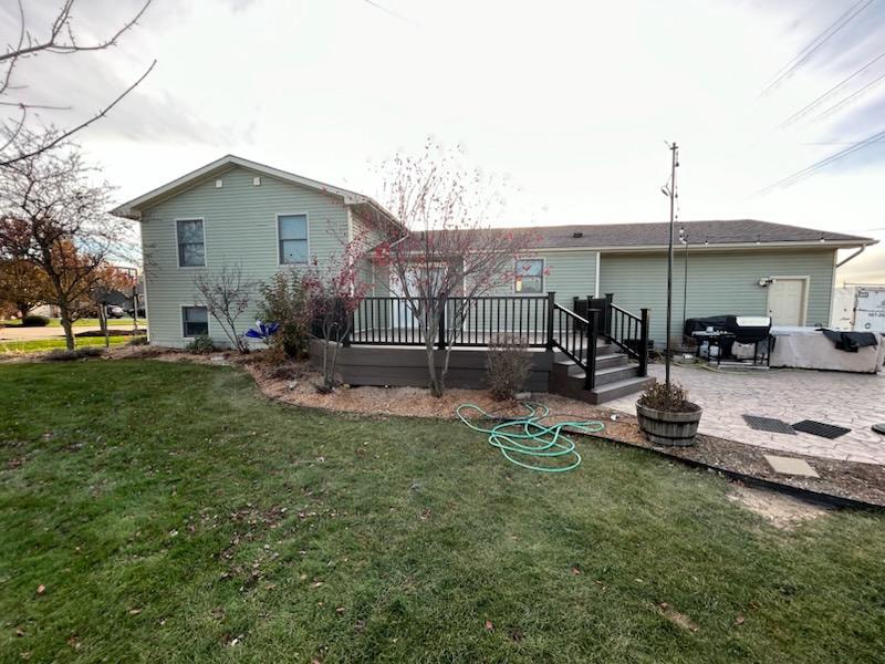 New composite deck — after: completed deck full rear view with black railing and stamped concrete patio — Findlay, Ohio