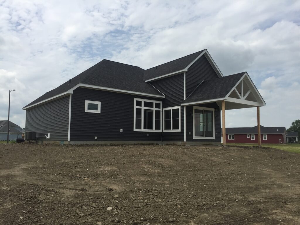 New construction composite siding Bowling Green — near complete: rear view with dark composite siding and covered porch, Bowling Green, Ohio
