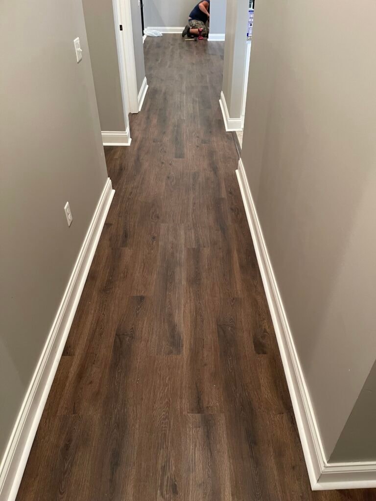 New LVP flooring — long hallway during installation with dark wood-look luxury vinyl plank and white baseboards, Findlay, Ohio