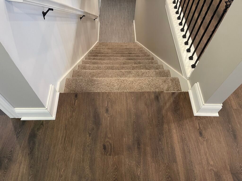 New LVP flooring — staircase landing with dark LVP on main floor transitioning to carpet on stairs, Findlay, Ohio