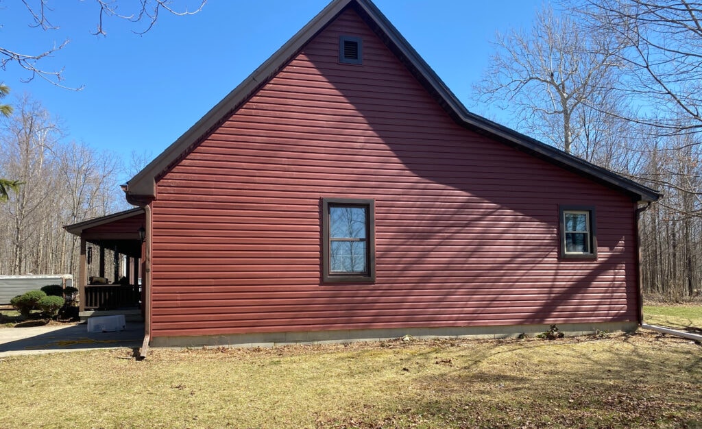 New siding Findlay — after: garage end gable of home with new dark red vinyl siding and dark trim, Findlay, Ohio