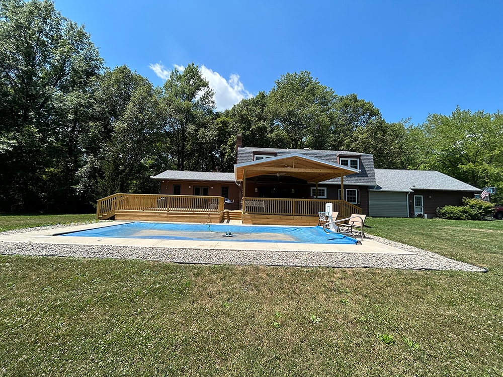 New treated deck with gable — full backyard view showing completed deck, gable, and pool from lawn