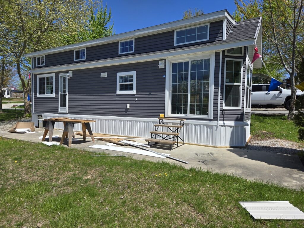 New treated deck with roof — before: park model side view with concrete pad under construction — campground