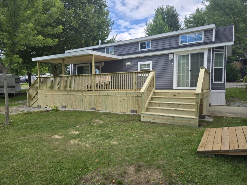 New treated deck with roof — completed side angle view with right staircase and partial roof — campground