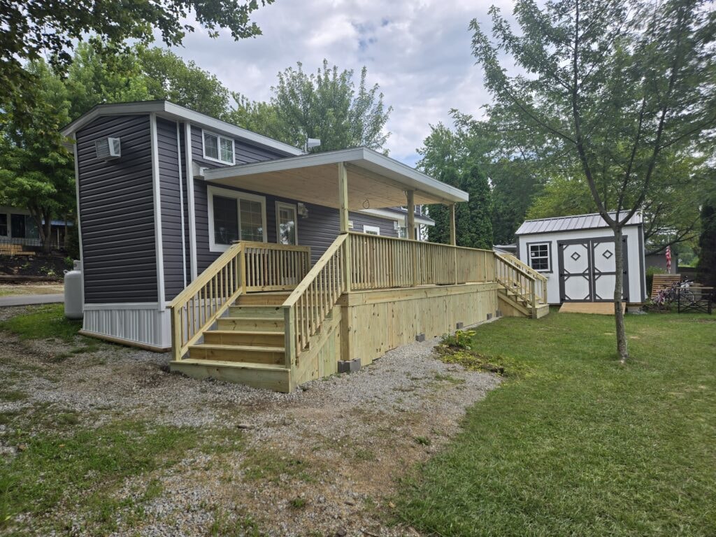 New treated deck with roof — completed left angle view with covered entry and storage shed — campground