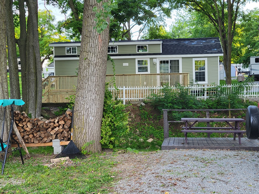 New treated deck — after: green park model with completed treated wood deck visible from distance — Wapakoneta campground