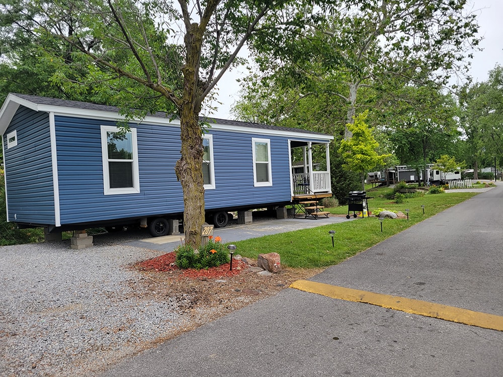 New treated deck — before: blue park model with small entry steps and no deck — Wapakoneta campground