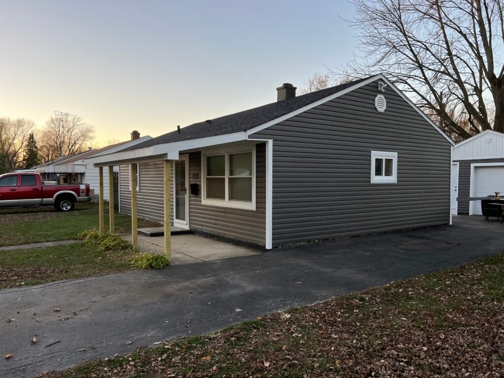 New vinyl siding — house front after installation with gray siding and rebuilt porch, Fostoria, Ohio