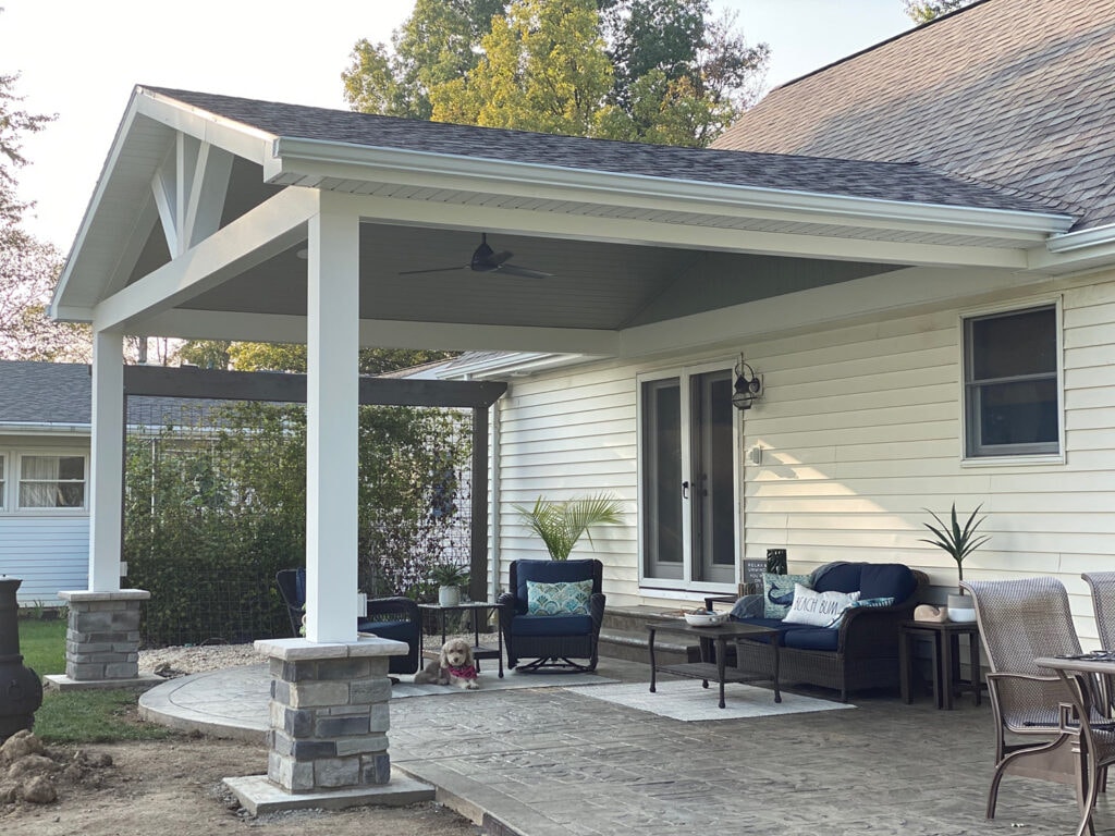 Finished open beam gable roof with stone columns over stamped concrete patio — Fostoria, Ohio