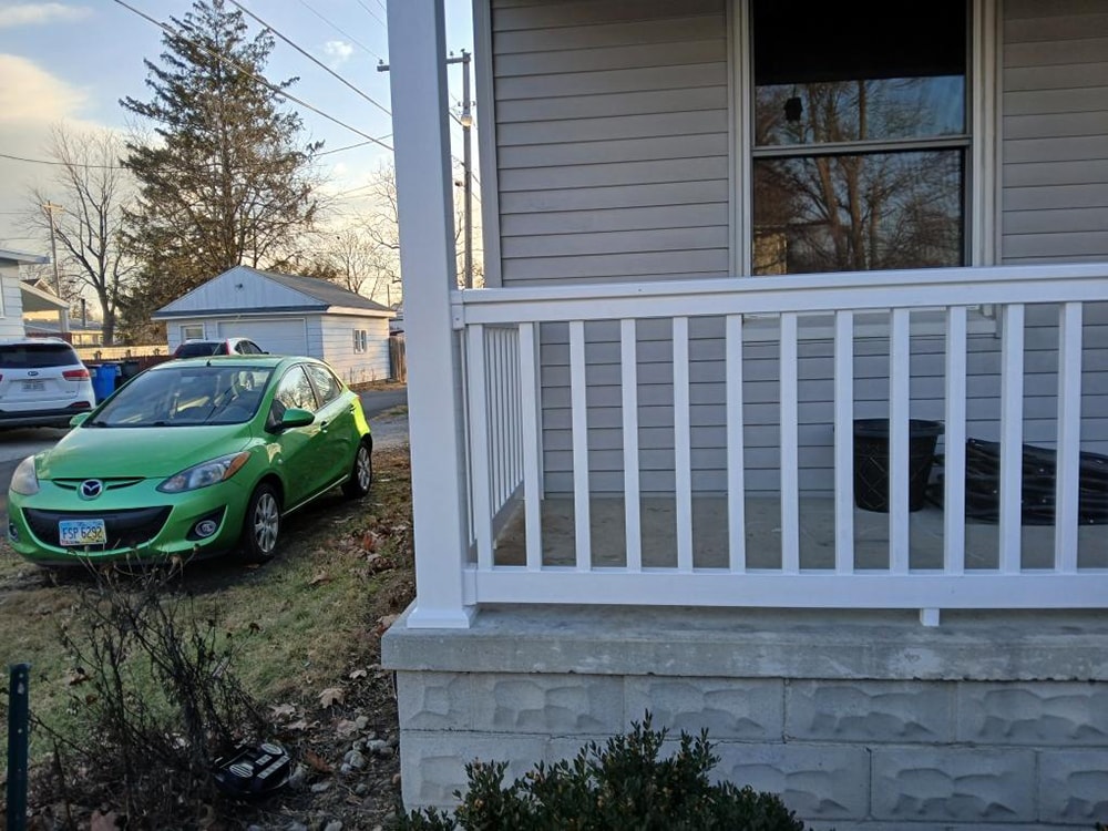 Porch railing replacement — after: side view of new white porch railing with green car in background — Findlay, Ohio