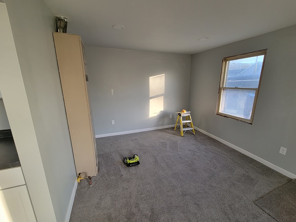 Rental home remodel during — bedroom with fresh gray paint, new carpet, and windows mid-installation, Findlay, Ohio