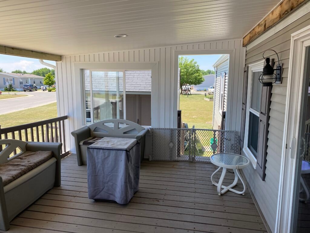 Roof addition existing deck Findlay — after: interior of covered deck section with white beadboard ceiling, recessed light, sliding glass door, and gray patio furniture, Findlay, Ohio