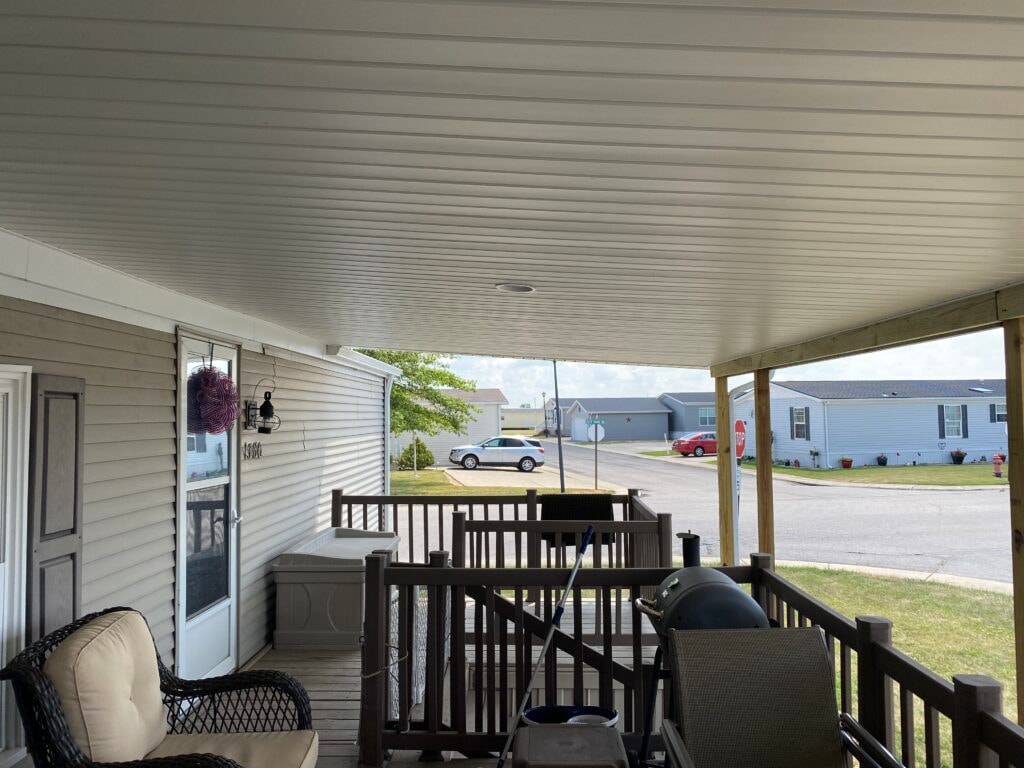 Roof addition existing deck Findlay — after: interior looking out from covered deck with white beadboard ceiling, recessed light, deck railing, covered grill, and neighborhood street view, Findlay, Ohio