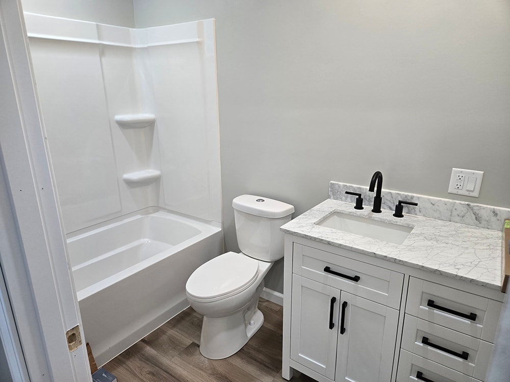 Home addition — completed master bathroom with white vanity, marble top, and black fixtures — Findlay, Ohio
